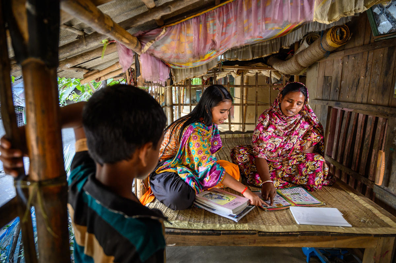 Shabitri practices her reading with her daughter. 
