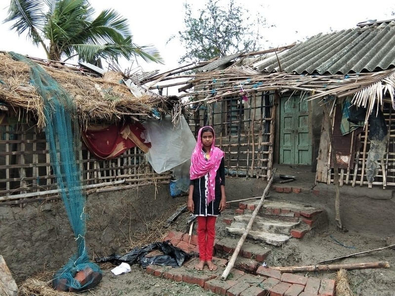 Girl in India stands outside home damaged by cyclone