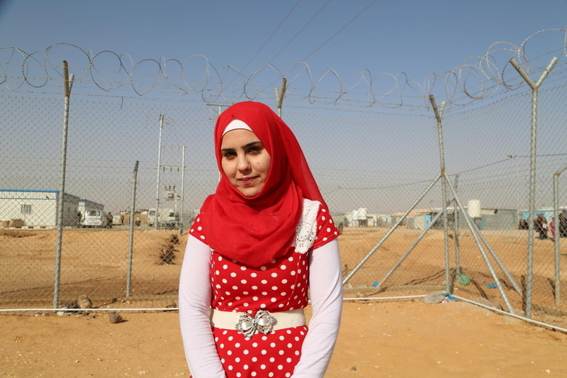 Young female refugee from Syria in front of a barbed wire fence