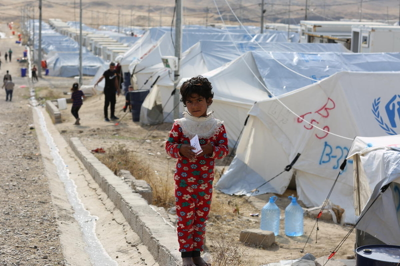 Young girl with refugee tents as background