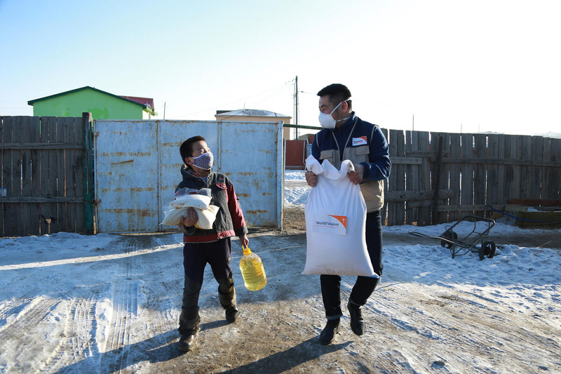 sponsored child and World Vision staff in Mongolia carry food supplies