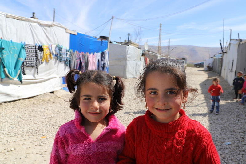 Two young Syrian refugee girls smiling